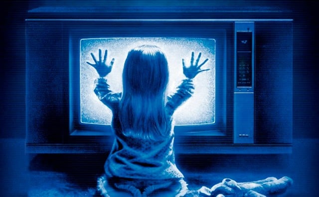 A young girl holds her hands up to a TV in Poltergeist