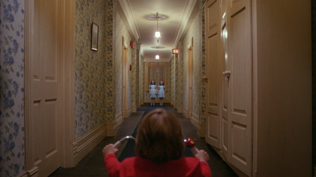 Twins stand at the end of a hallway in The Shining