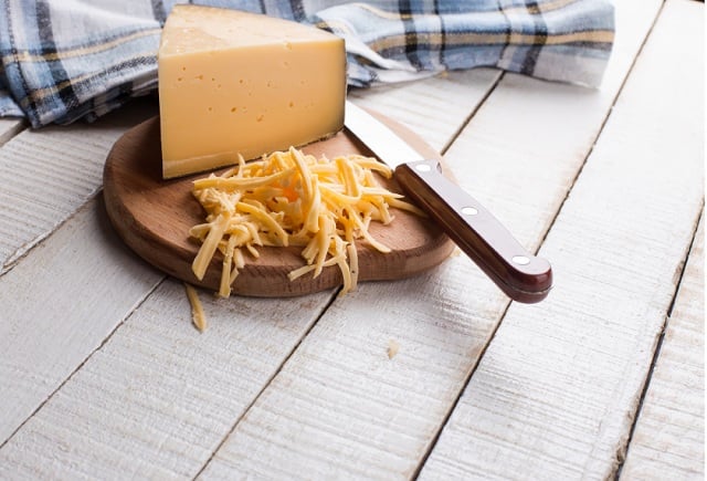 Shredded Gouda cheese on a cutting board
