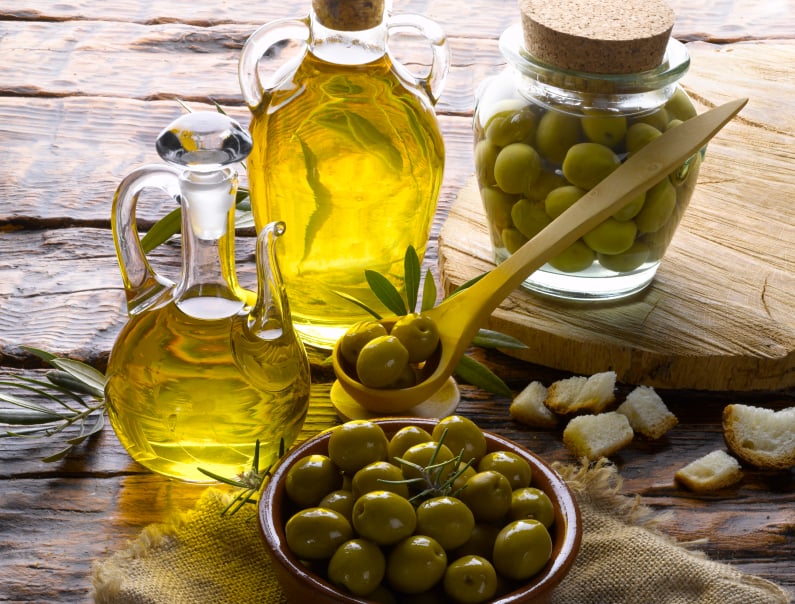 olives next to olive oil on a table