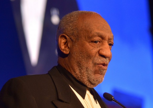 Bill Cosby is speaking at a microphone.