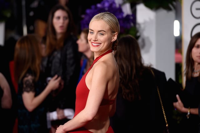 Taylor smiling in a red dress on the red carpet