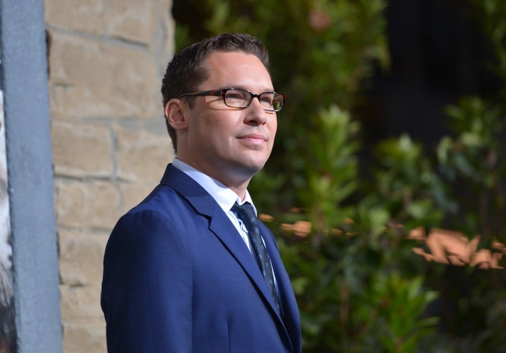 Bryan Singer, wearing a blue suit and glasses, looking to the right of the frame