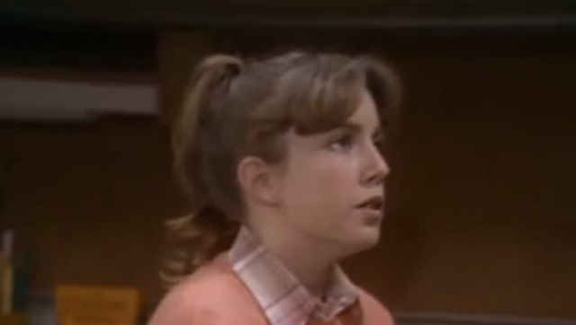 Dana Plato wearing a pink sweater, looking to the right of the frame