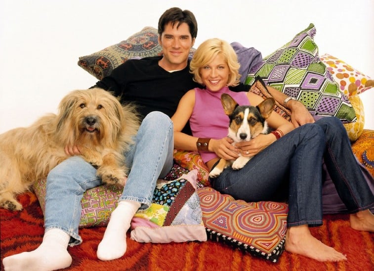 Dharma and Greg lay on a pile of pillows while holding their dogs in Dharma and Greg