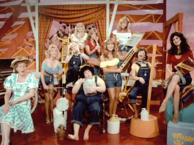 A group of women play instruments in overalls in Hee Haw Honeys