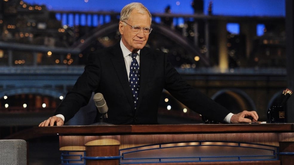 David Letterman is sitting at his desk on The Late Show.