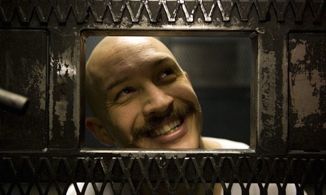 Tom Hardy smiles while looking out the window of a jail cell in Bronson