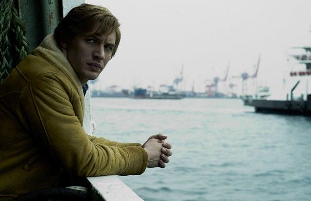 Tom Hardy leans on a railing while looking to on the water in Tinker Tailor Soldier Spy
