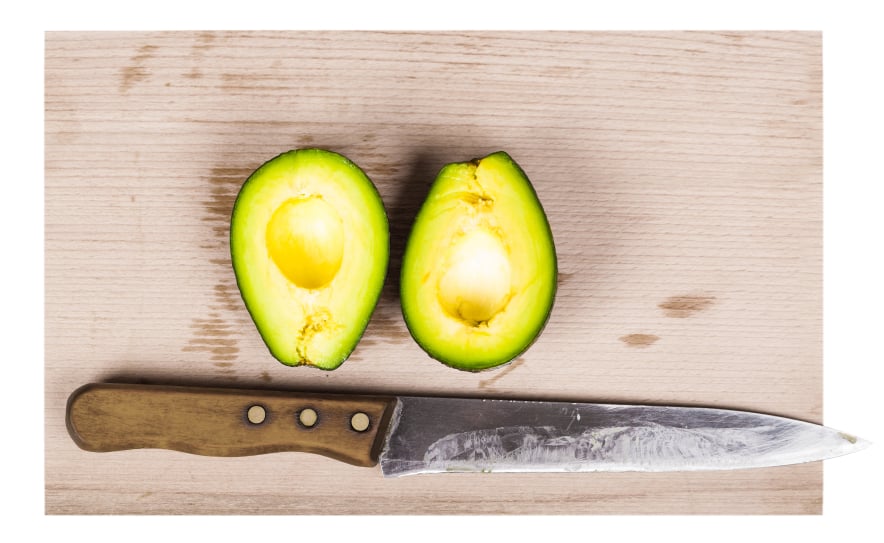 Avocado halved on a table with a knife