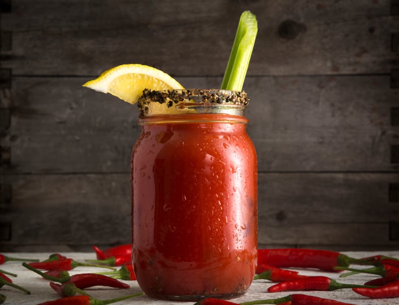 bloody mary garnished with a peppercorn rim, lemon, and a celery stalk