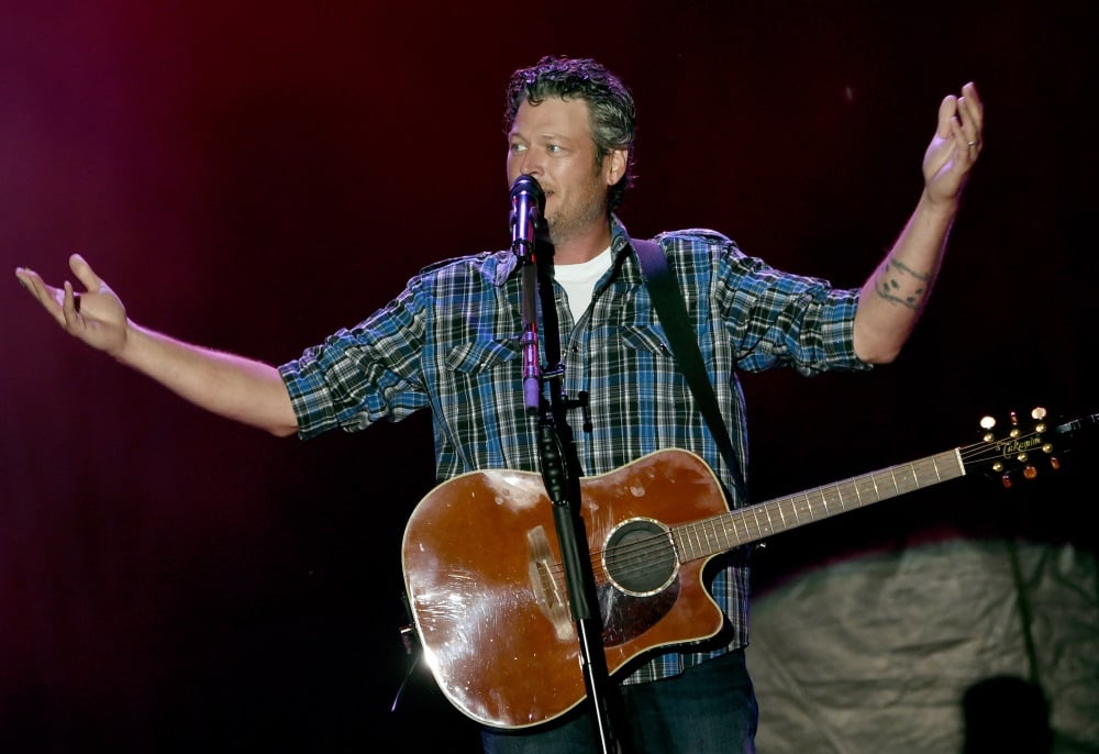 Blake Shelton holds his hands up as he performs on stage.