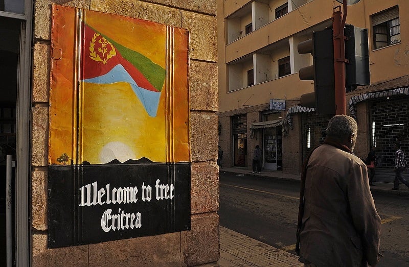 A man waits to cross the road beside a patriotic poster in Asmara, Eritrea