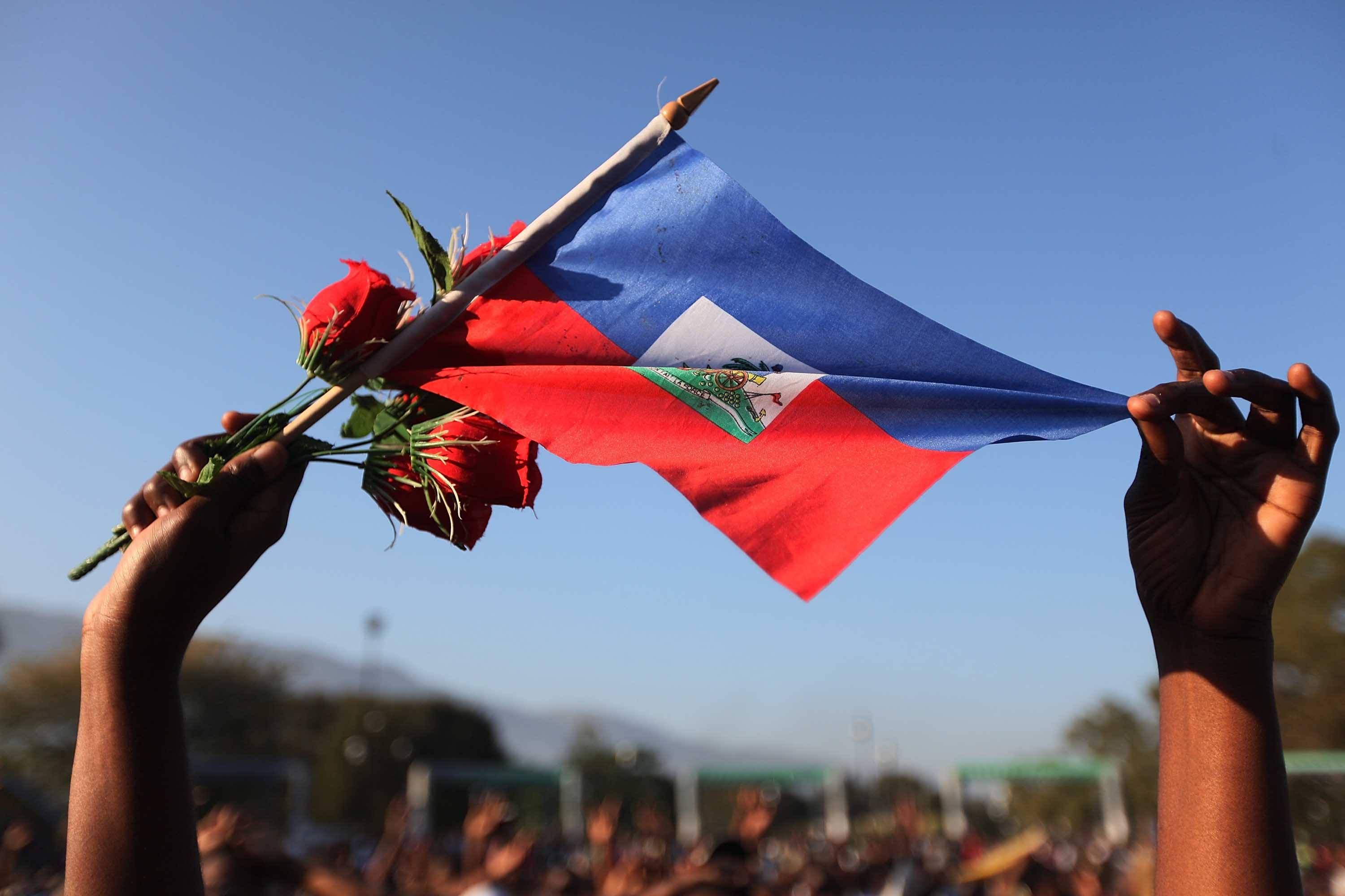 A woman holds a Haitian flag and roses