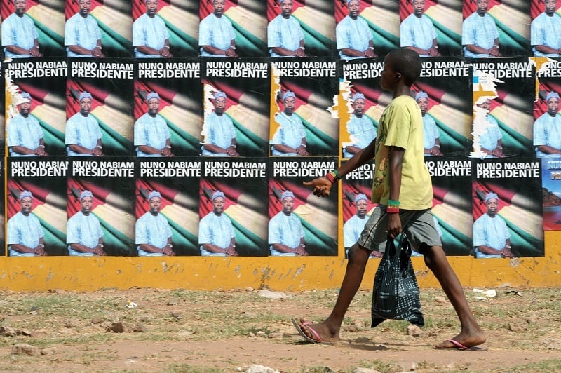 A boy passes by electoral posters in the Republic of Guinea-Bissau