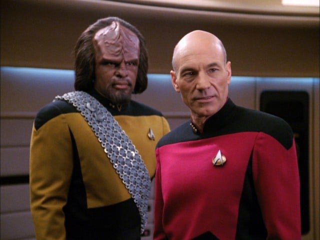 Picard and Worf, both looking to the right of the frame on the bridge of the Enterprise