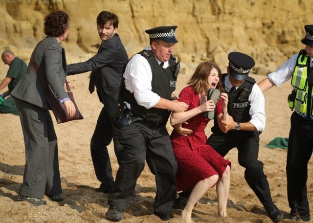 Two police officers drag a screaming Beth Latimer away from the crime scene as Detectives Benson and Hardy stand nearby in a scene from the first episode of 'Broadchurch.'