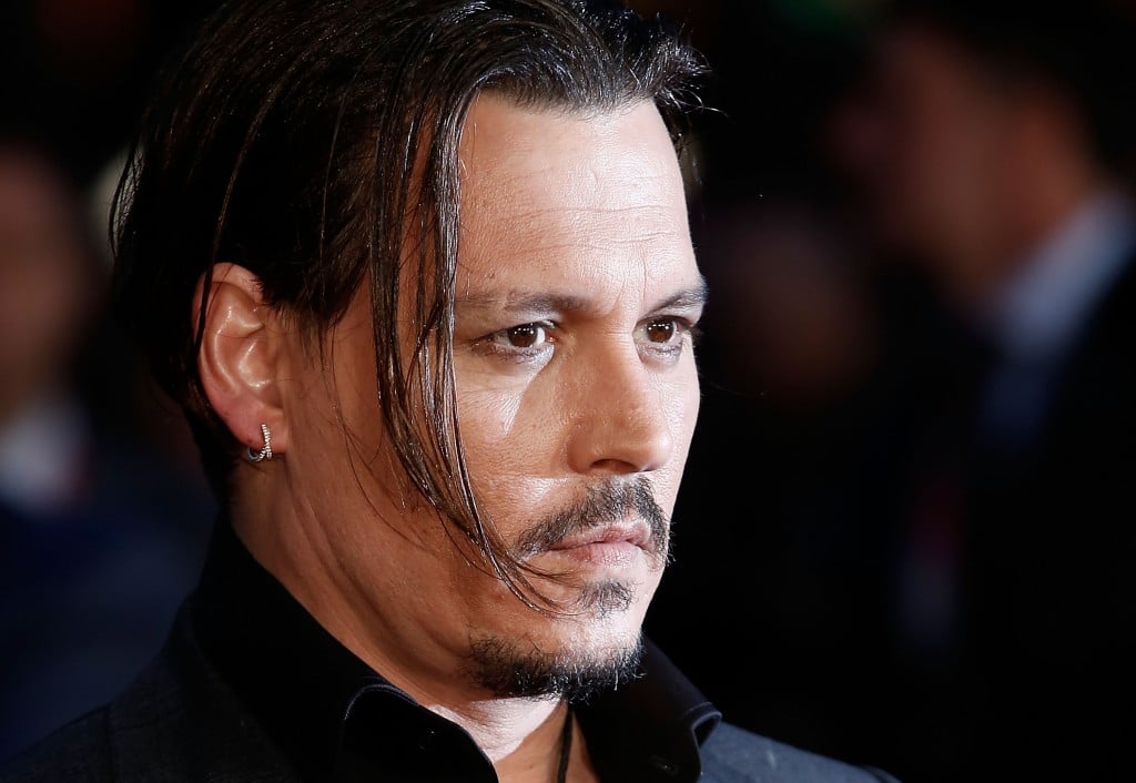 Johnny Depp with a lock of long hair hanging over his face, looking to the right of the frame