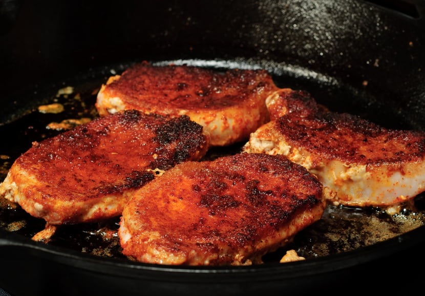 Pork chops cooking in a pan