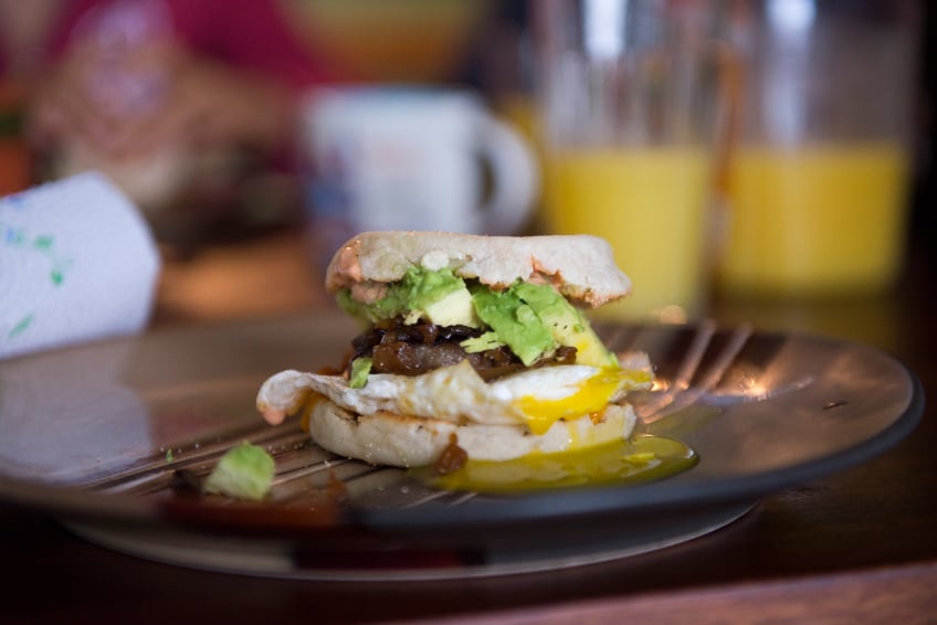 breakfast sandwich with egg, sausage, and avocado, english muffin