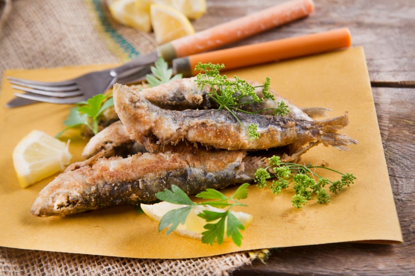 fried sardines with lemon and parsley on parchment paper