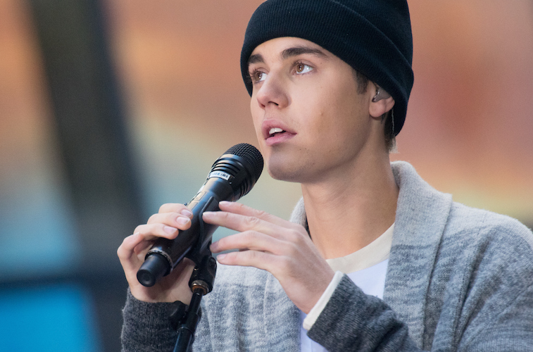 Young man in a black cap and gray sweater holding a microphone