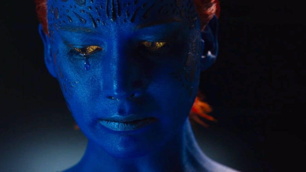 Jennifer Lawrence as Mystique, with blue skin and orange hair, sadly looking down and to her right