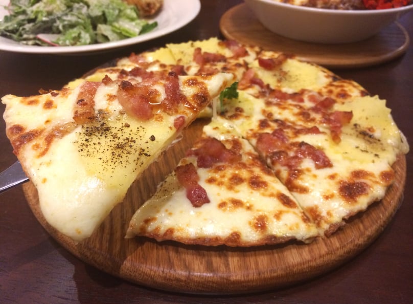 slice of bacon and potato pizza on a wooden pizza peel