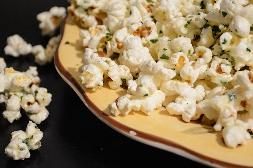 close up of Garlic Parmesan Popcorn with parsley in a yellow bowl