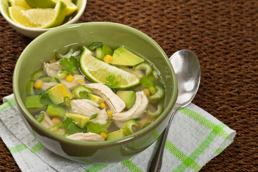 bowl of chicken and avocado soup with corn, cilantro, and lime