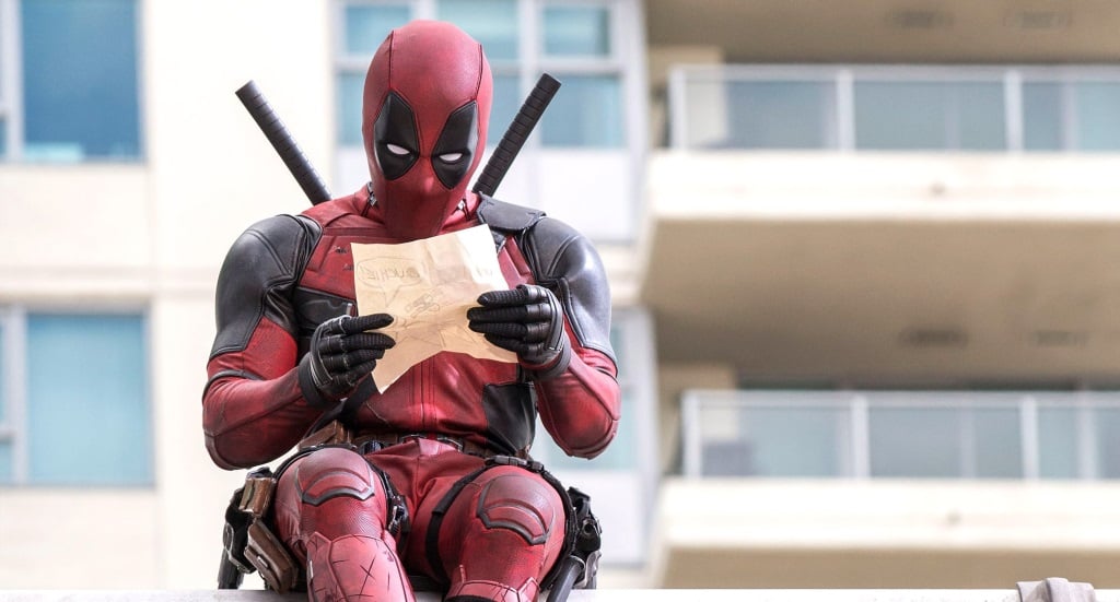 Deadpool looks at a piece of paper while in uniform