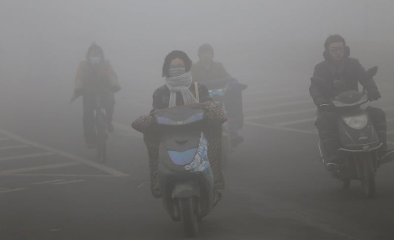 Chinese commuters ride through polluted air