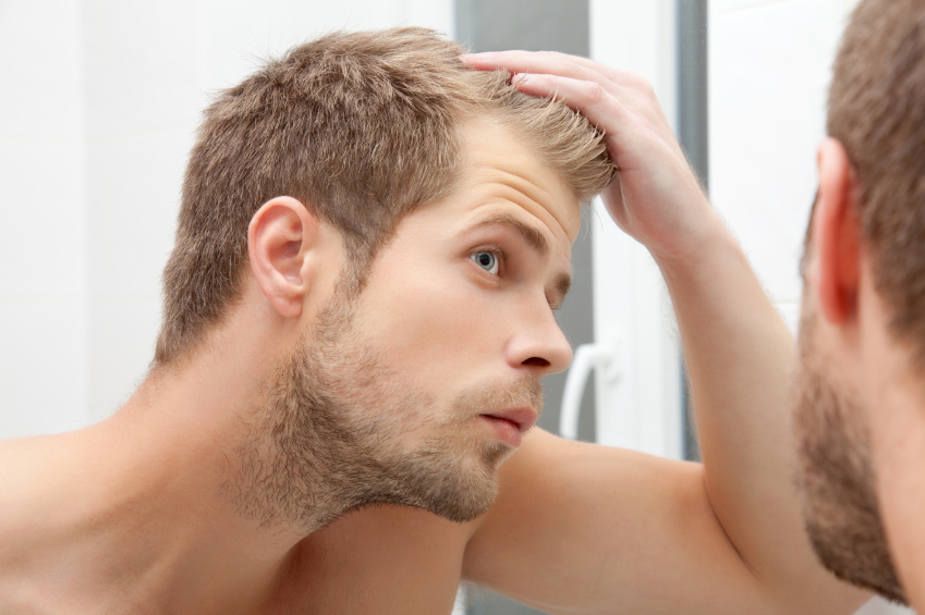 Young man looking at his hairs in mirror