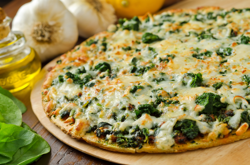 thin-crust spinach pizza ready to be sliced