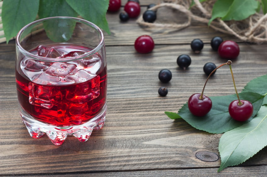 iced cherry drink on a wooden table with berries