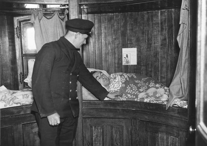 black and white photo of a train conductor waking up someone