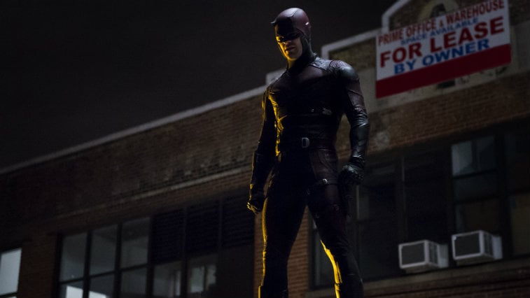Daredevil in his full suit, standing on a rooftop and looking down