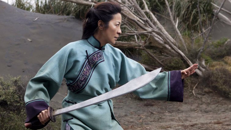 Yu Shu Lien is in a stance holding up one hand and a samurai sword in the other.