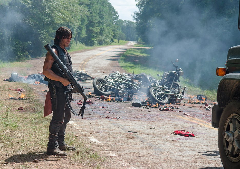 Daryl with a rocket launcher standing on the road after a massive motorcycle collision