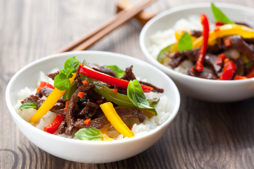 beef and pepper stir fry in white bowls with rice