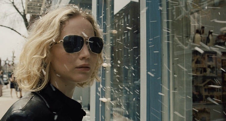 Jennifer Lawrence wears sunglasses and stands outside a store window in Joy