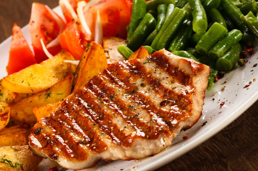 grilled pork chops with herbs served with potatoes and green beans