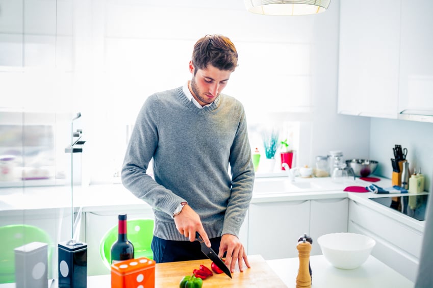 young man cutting vegetables in kitchen