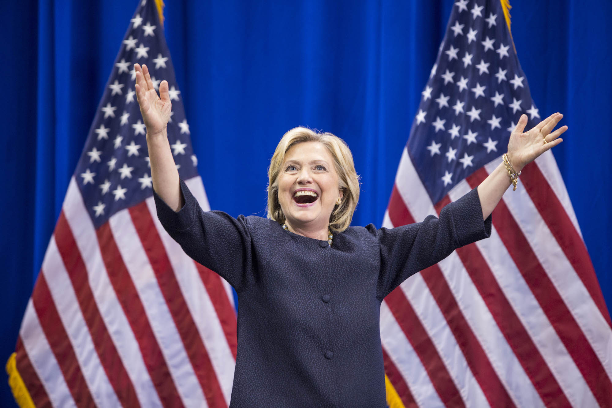 Democratic presidential candidate Hillary Clinton raises her arms stands on stage as voters prepare to vote for Democrats or Republicans