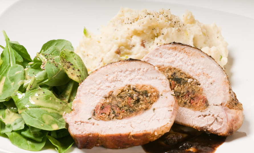 pork roast with a savory filling served with potatoes and green vegetables