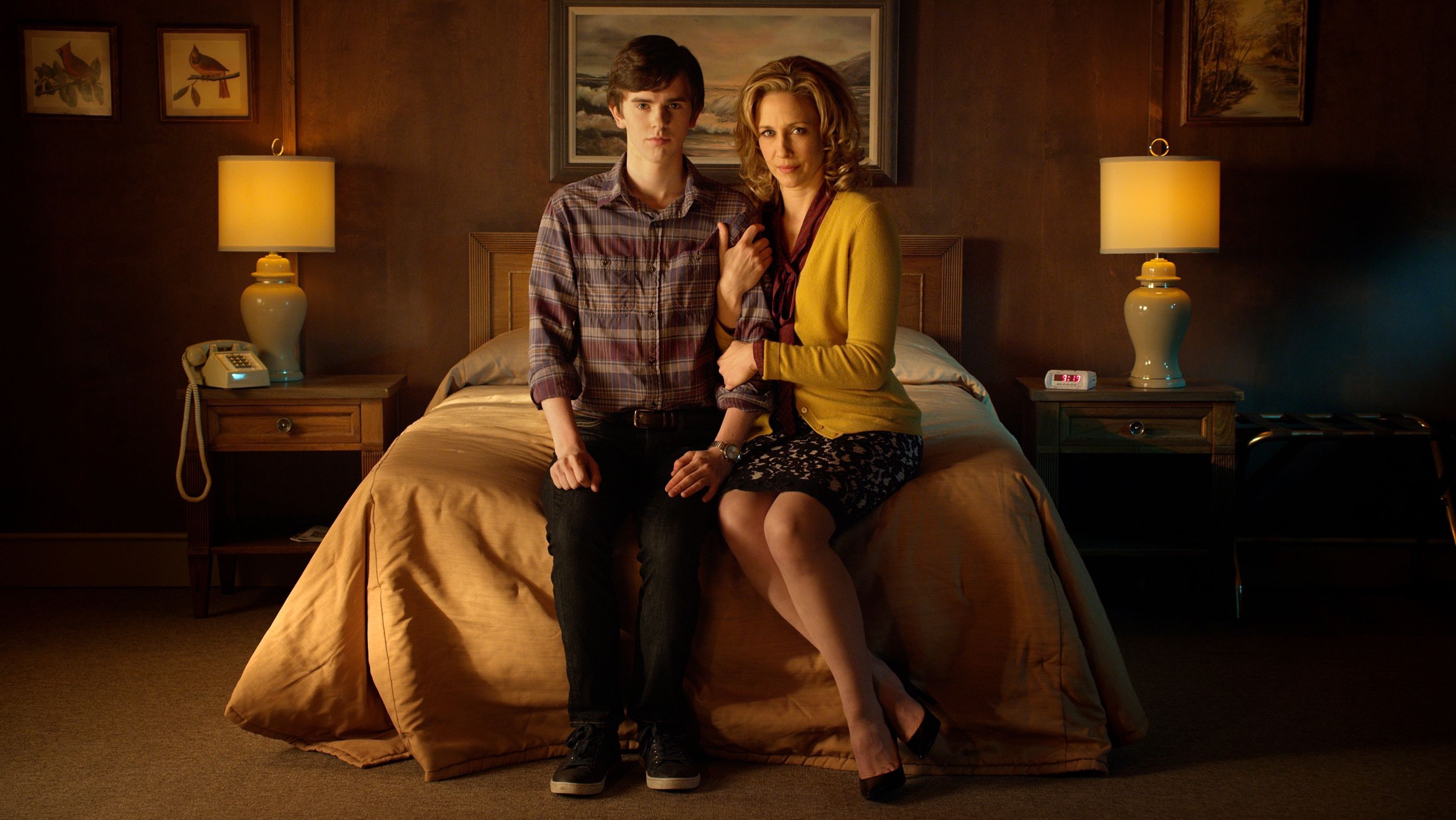 Norma (Vera Farmiga) and Norman (Freddie Highmore) sitting on a bed in A&E's Bates Motel