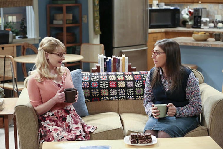 Melissa Rauch and Mayim Bialik talk on a couch in a scene from The Big Bang Theory |