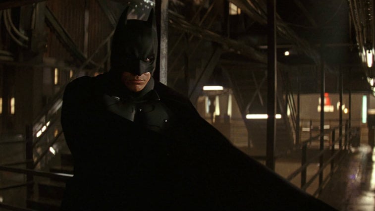 Christian Bale stands in his Batman suit in Batman Begins