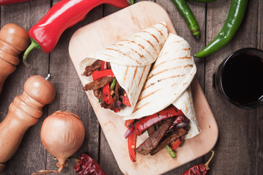 Fajitas on wooden board with vegetables