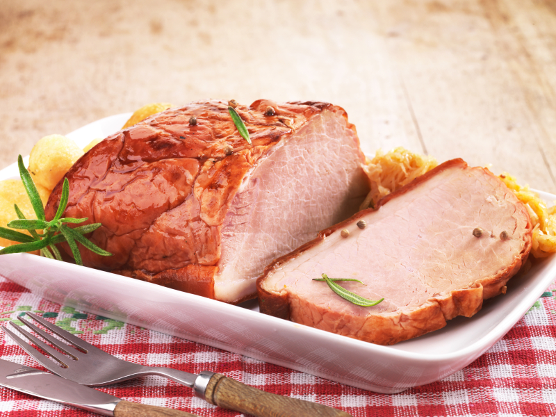 Pork loin on white plate with fork and knife